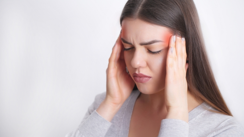 Woman holding her temples in pain, showing signs of a migraine