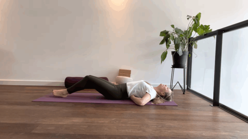 Person practicing restorative yoga for migraines in a supported backbend on a yoga mat