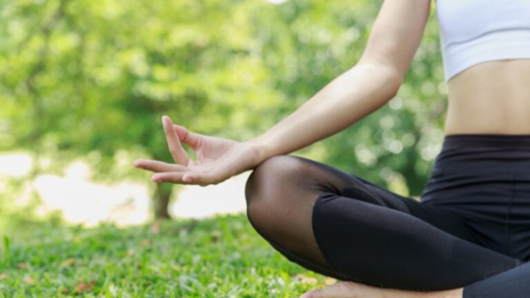 Person practicing yoga for migraine relief outdoors